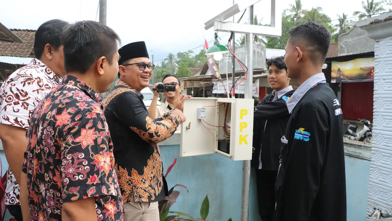 Kepala Desa Sidomulyo Kamiludin melihat langsung alat aplikasi SI-AMA di depan balai Desa Sidmulyo Jember. (Istimewa)