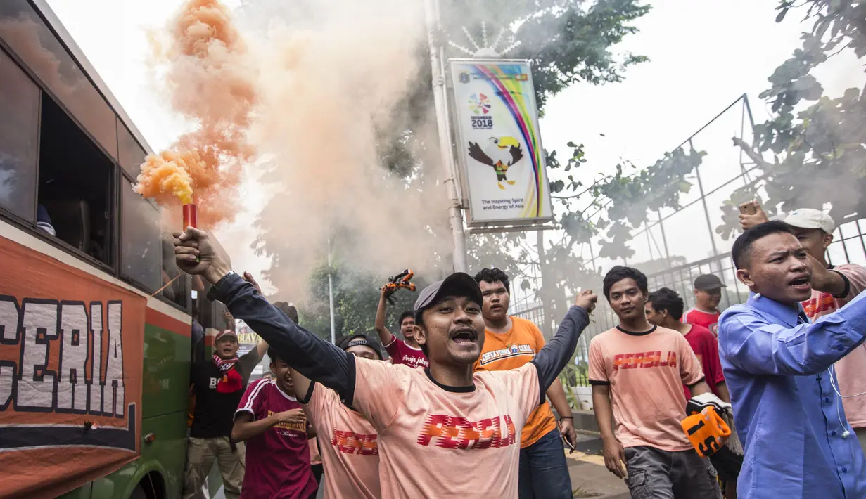 Suporter Persija Jakarta, The Jakmania, menyalakan flare saat akan menonton laga Liga 1 melawan Mitra Kukar di Senayan, Jakarta, Minggu (9/12). Persija berpeluang besar menjadi juara jika berhasil menang. (Bola.com/Vitalis Yogi Trisna)