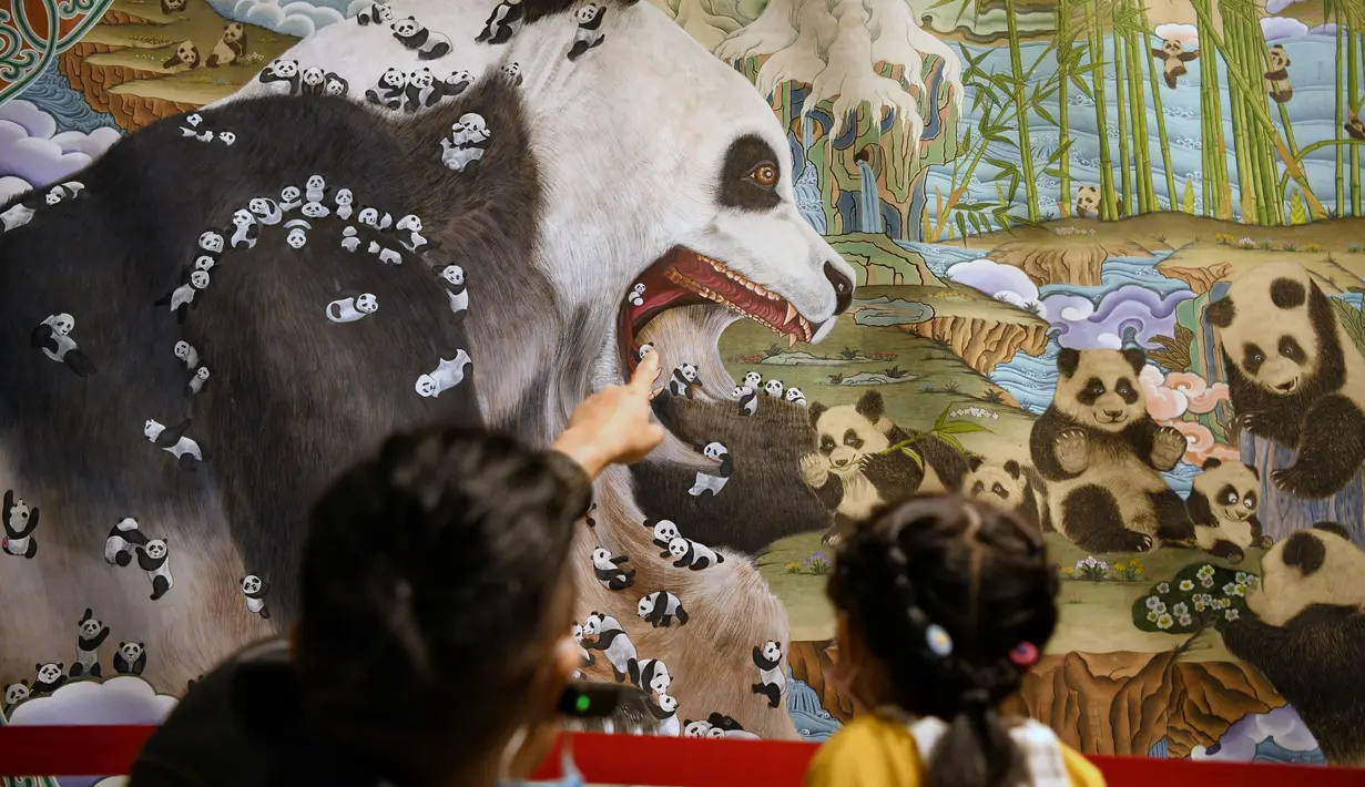 Pengunjung mengamati lukisan thangka bertema panda di Perpustakaan Provinsi Sichuan, Chengdu, Provinsi Sichuan, China, 11 Oktober 2020. Lebih dari 40 pelukis thangka menghabiskan waktu setahun untuk menyelesaikan lukisan yang memiliki panjang 172 meter dan tinggi 2,6 meter tersebut. (Xinhua/Wang Xi)