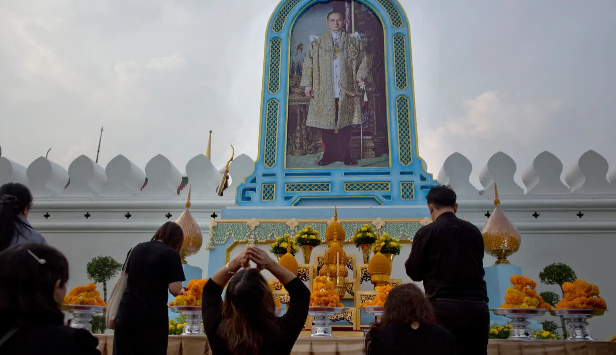 Warga Thailand memberi penghormatan di depan potret mendiang Raja Thailand Bhumibol Adulyadej di luar Grand Palace, Bangkok, Thailand (13/10). Upacara ini untuk memperingati satu tahun wafatnya Raja Bhumibol Adulyadej. (AP Photo/Gemunu Amarasinghe)