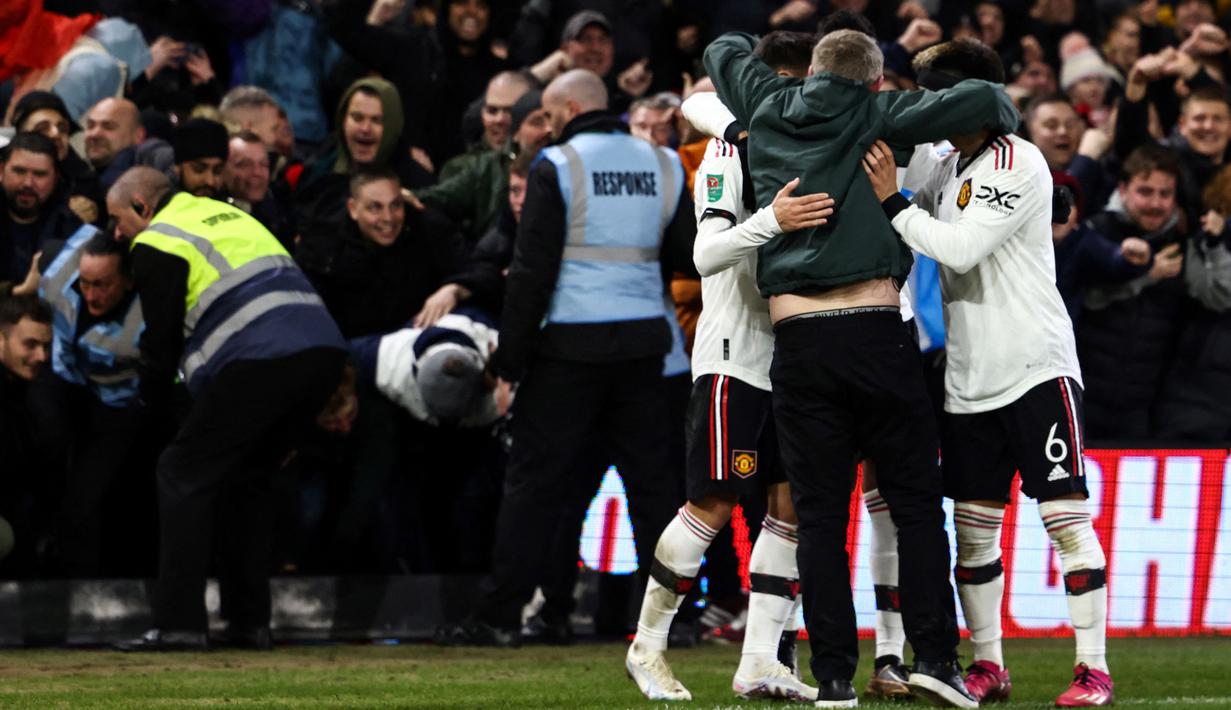 Setelah berhasil masuk lapangan, suporter tersebut melakukan selebrasi bersama ketiga pemain MU dengan memeluknya. (AFP/Darren Staples)