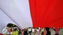 Seorang peserta 'Aksi Kita Indonesia' membentangkan Bendera Merah Putih raksasa di Bundaran HI, Jakarta, Minggu (4/12). Mereka juga membawa berkeliling Bendera Merah Putih raksasa sambil meneriakkan 'Kita Indonesia'. (Liputan6.com/Angga Yuniar)
