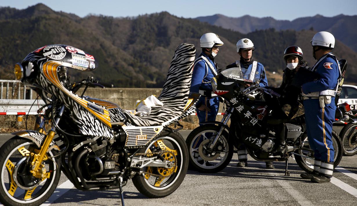 Petugas kepolisian saat menilang rombongan touring motor Bousouzoku di daerah Yamanashi, Jepang , (3/1). Mesikpun motor tahun 1950-an ini ilegal berkendara di Jepang tetapi puluhan pengemudi motor ini tetap melakukan touring. (REUTERS / Thomas Peter)