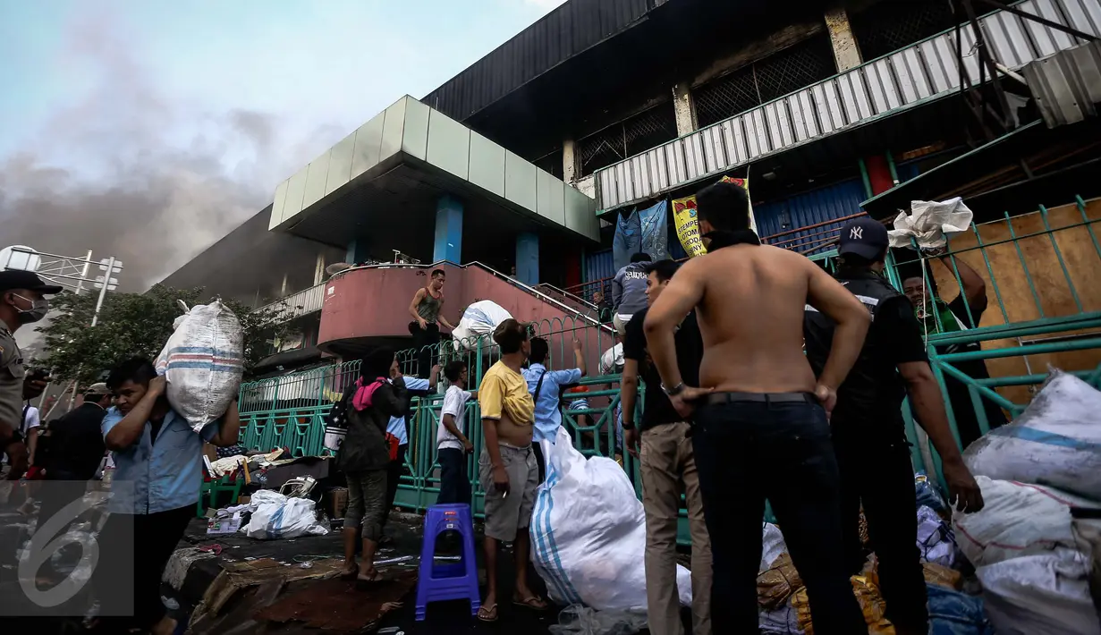 Sejumlah pedagang sibuk menyelematkan barang dagangannya saat kebakaran besar melanda Pasar Senen, Jakarta Pusat, Kamis (19/1). Kebakaran di kios asesoris Pasar Senen terjadi sekitar pukul 04.30 WIB. (Liputan6.com/Faizal Fanani)