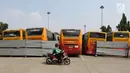 Pengemudi ojek online melintas dekat bangkai bus Transjakarta yang mangkrak di terminal Pulogadung, Jakarta, Jumat (23/8/2019). Menurut petugas, sebanyak 36 bus transjakarta yang sudah terparkir sejak Oktober 2017 tersebut berada dalam kondisi rusak dan tidak terawat. (Liputan6.com/Herman Zakharia)