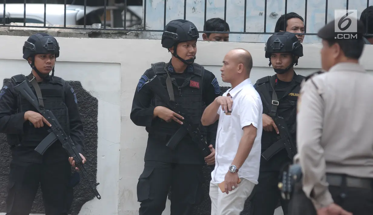 Personel Brimob bersenjata lengkap berjaga di depan gerbang masuk PN Jakarta Selatan saat sidang pembacaan tuntutan terhadap terdakwa sejumlah kasus tindak pidana terorisme, Aman Abdurrahman, Jumat (18/5). (Liputan6.com/Helmi Fithriansyah)