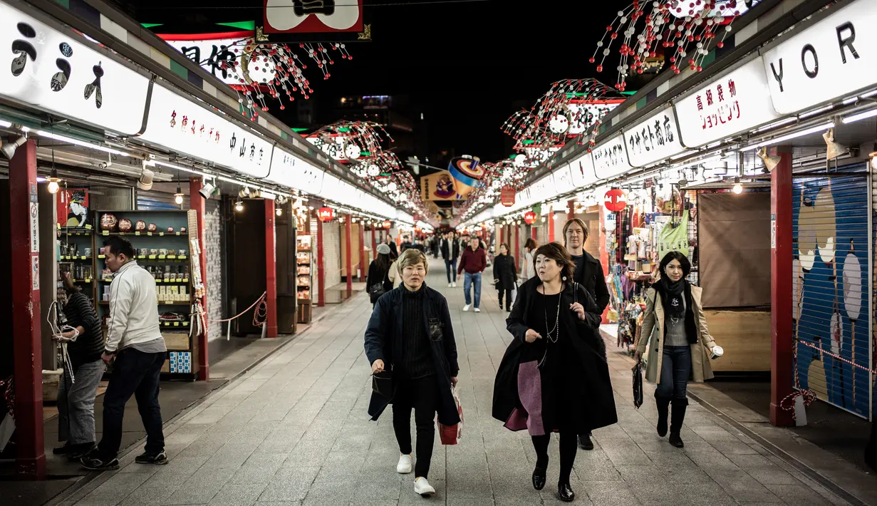 Orang-orang berjalan di jalan daerah Asakusa di Tokyo (1/12). Asakusa mempunyai bangunan dari tahun 1950-an dan 1960-an berbanding kawasan lain di Tokyo. (AFP Photo/Martin Bureau)