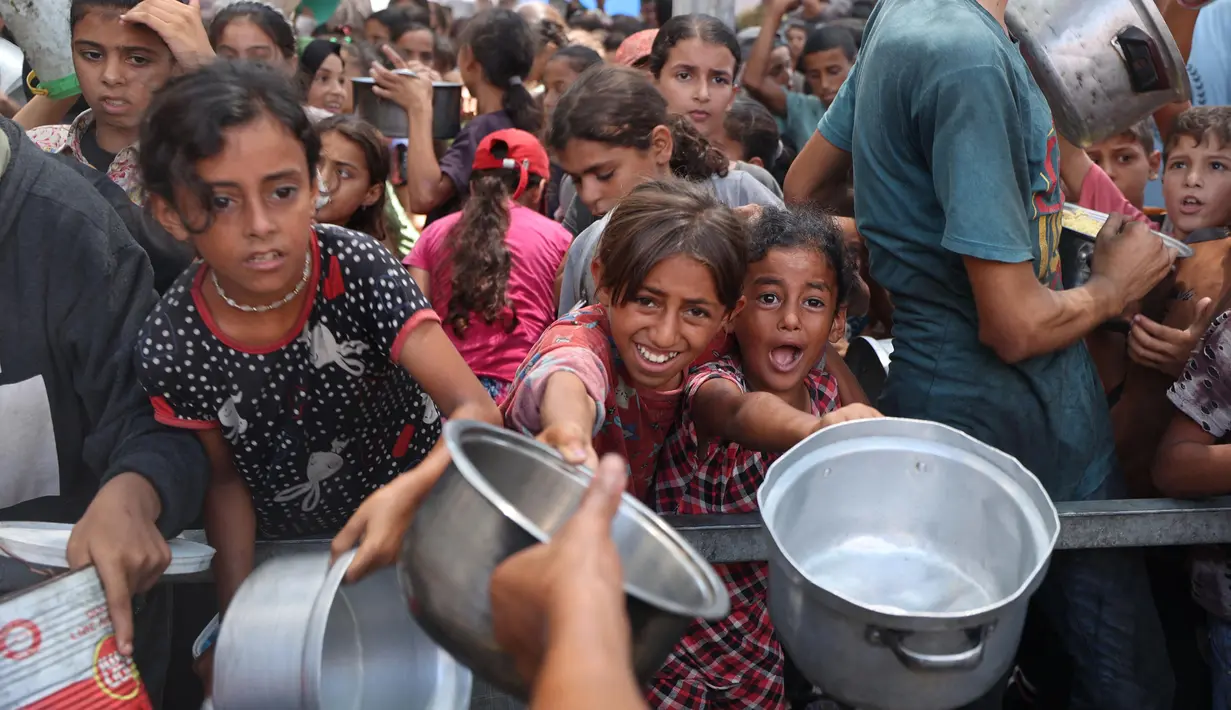 Anak-anak perempuan Palestina berkumpul untuk menerima makanan matang dari pusat distribusi makanan di kamp pengungsi Nuseirat di Jalur Gaza tengah pada 18 Agustus 2025. (Eyad BABA/AFP)