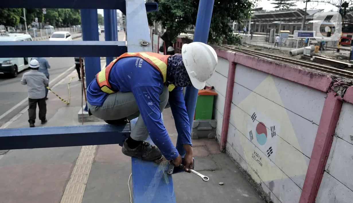 Pekerja menyelesaikan pembangunan jembatan penyeberangan orang (JPO) di dekat Stasiun Jatinegara, Jakarta, Senin (11/5/2020). JPO yang ditargetkan rampung pada tahun ini tersebut sekaligus menjadi jalur keluar penumpang kereta Stasiun Jatinegara. (merdeka.com/Iqbal S. Nugroho)