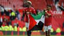 Tak lama berselang, Amad Diallo mengikuti Pogba untuk bersama-sama membentangkan bendera tersebut dan menunjukkannya ke arah penonton di tribun Old Trafford. (Foto: AFP/Pool/Phil Noble)