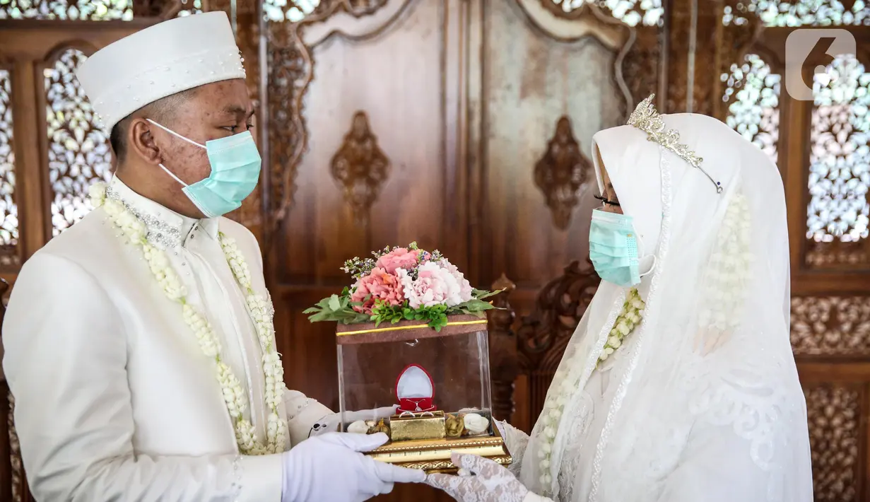 Pasangan pengantin usai melaksanakan prosesi akad nikah di KUA Jagakarsa, Jakarta, Sabtu (6/6/2020). Pernikahan mengikuti protokol kesehatan sesuai Surat Edaran (SE) Menteri Agama Nomor 15 Tahun 2020. (Liputan6.com/Faizal Fanani)