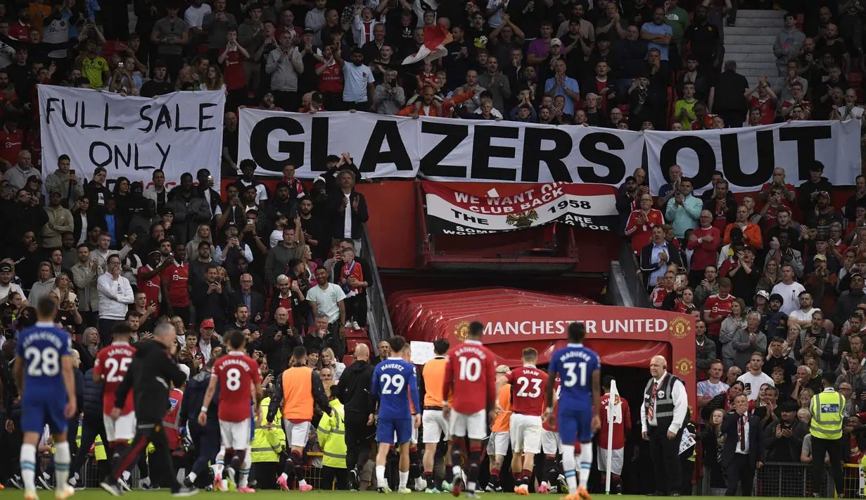 Spanduk bertuliskan "Glazer Out" terpampang di salah satu sisi stadion Old Trafford dalam laga tunda pekan ke-32 Liga Inggris 2022/2023 antara MU melawan Chelsea, Jumat (26/5/2023). (AFP/Oli Scarff)