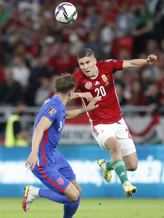 Pemain Inggris John Stones (kiri) berebut bola dengan pemain Hungaria Roland Sallai pada pertandingan sepak bola Grup I kualifikasi Piala Dunia 2022 di Puskas Ferenc Arena, Budapest, Hungaria, Kamis (2/9/2021). Inggris menang 4-0. (AP Photo/Laszlo Balogh)