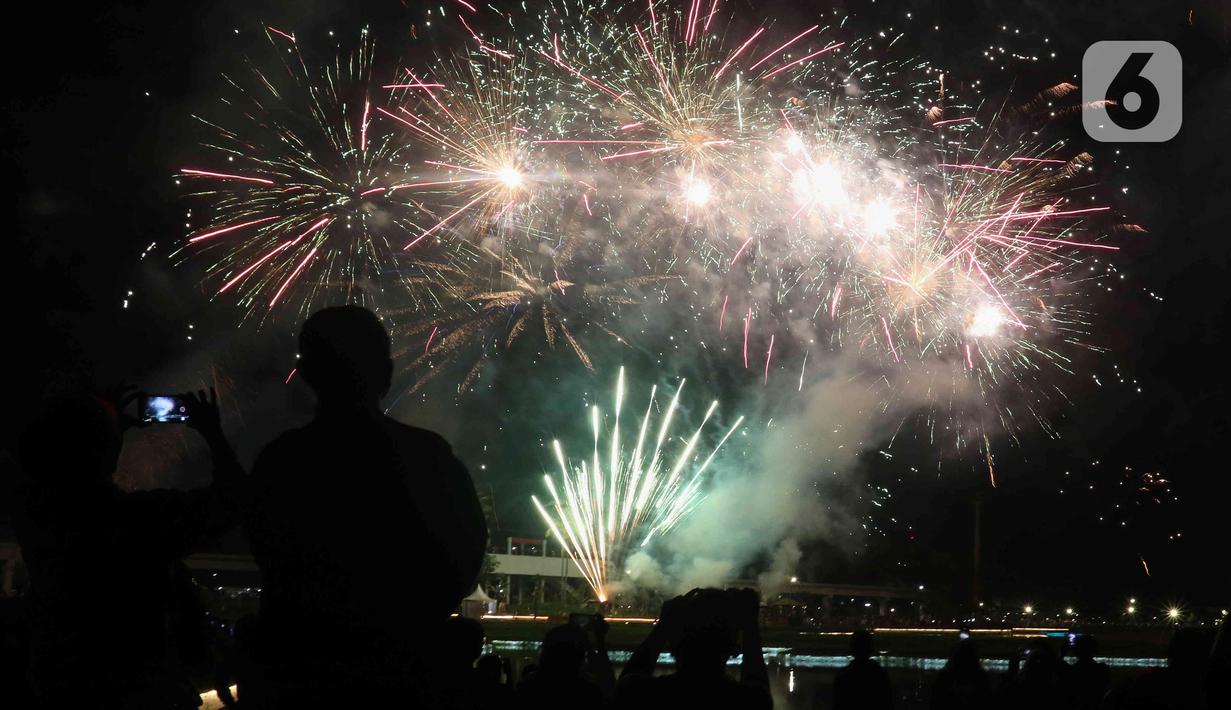 Warga menyaksikan pesta kembang api saat perayaan malam puncak Tahun Baru 2023 di Danau Archipelago, Taman Mini Indonesia Indah (TMII), Jakarta, Minggu (1/1/2023). Perayaan malam puncak Tahun Baru 2023 yang digelar Pemerintah Provinsi DKI Jakarta di TMII menghadirkan pesta kembang api yang berlangsung selama 15 menit. (Liputan6.com/Herman Zakharia)
