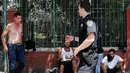 Petugas polisi berdebat dengan para pecandu ganja sintetis saat hendak ditertibkan pinggir jalan East Harlem, New York (5/8/2015). Pada 2012 Amerika Serikat melarang pembuatan K2 atau ganja sintetis. (AFP PHOTO/SPENCER PLATT)