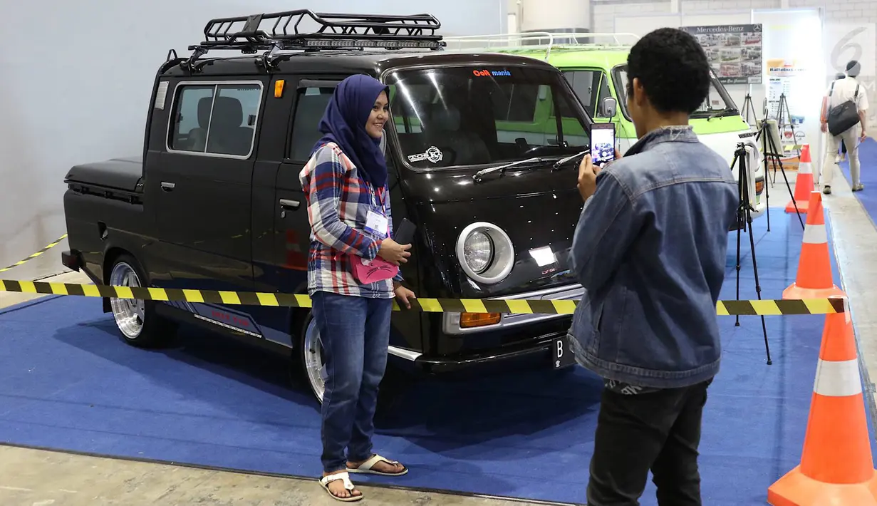 Pengunjung berpose dengan kendaraan yang dipajang dalam pameran Indonesia Classic N Unique Bus 2019 di JIExpo Kemayoran, Jakarta, Rabu (20/3). Pameran ini merangkai sejarah transportasi di Indonesia. (Liputan6.com/Immanuel Antonius)