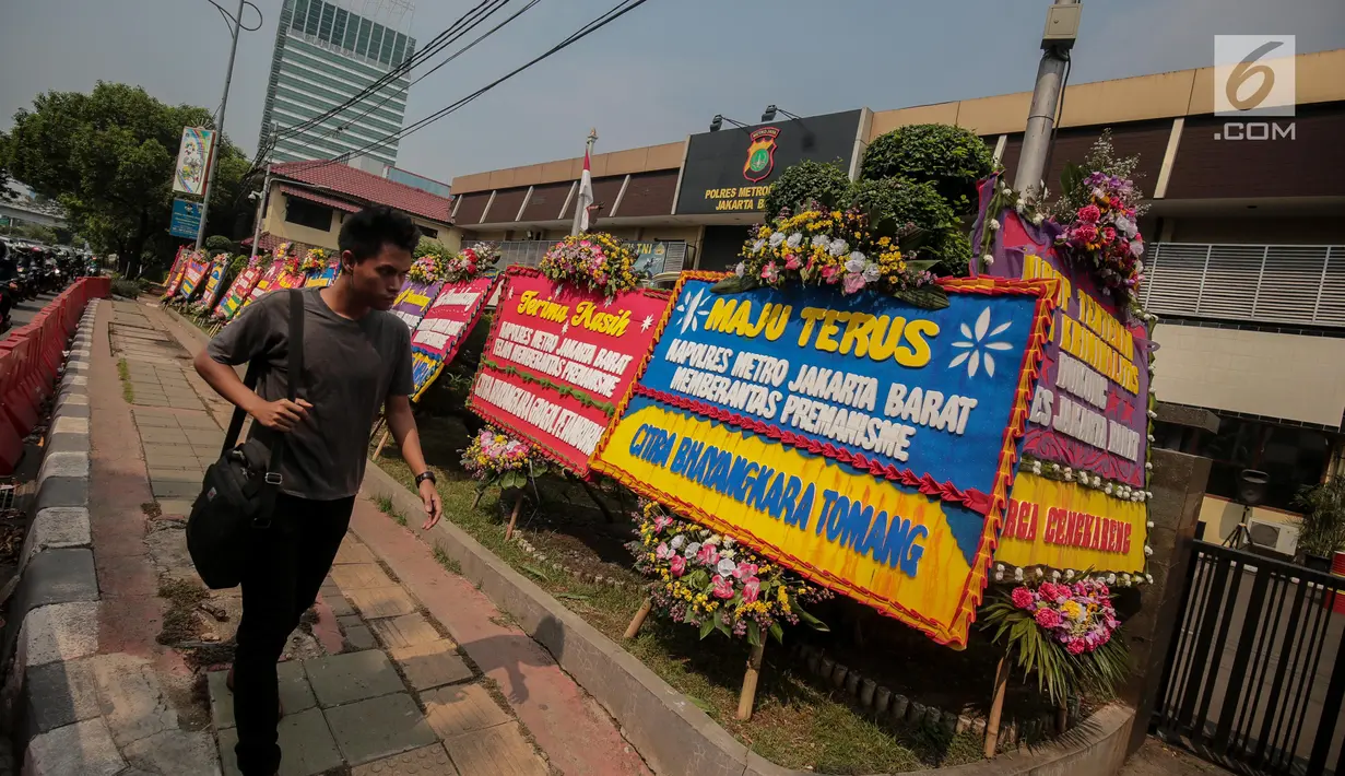 Warga melintasi karangan bunga di Halaman Polres Jakarta Barat, Jumat (23/11). Puluhan karangan bunga yang dikirimkan warga tersebut diberikan guna mendukung pihak kepolisian dalam memberantas aksi premanisme di Jakarta Barat. (Liputan6.com/Faizal Fanani)