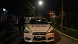 Mobil polisi terparkir di jalan menuju rumah mantan Perdana Menteri Malaysia, Najib Razak di Kuala Lumpur, Rabu (16/5). Polisi melakukan penggeledahan terkait dugaan pencucian uang di kediaman Najib usai Salat Tarawih. (AFP/Mohd RASFAN)