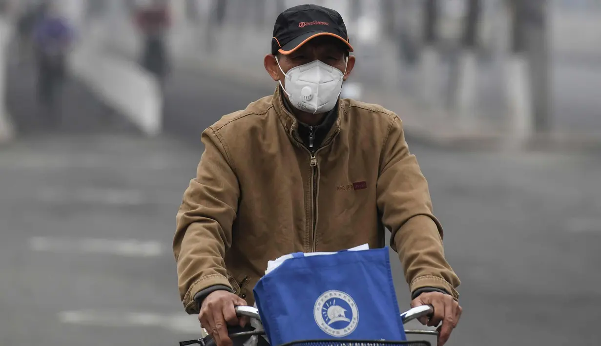 Seorang pria mengenakan masker mengendarai sepedanya di jalan pada hari yang tercemar polusi udara di Beijing, China (2/4). (AFP Photo/Fred Dufour)