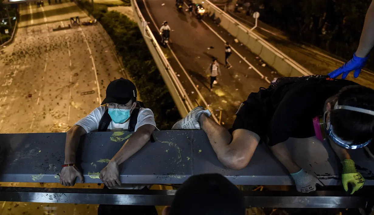 Demonstran menuruni jembatan menggunakan tali untuk melarikan diri dari Universitas Politeknik Hong Kong di Distrik Hung Hom, Hong Kong, Senin (18/11/2019). Lusinan demonstran melarikan diri dari Universitas Politeknik Hong Kong yang dikepung polisi selama berhari-hari. (Ye Aung Thu/AFP)