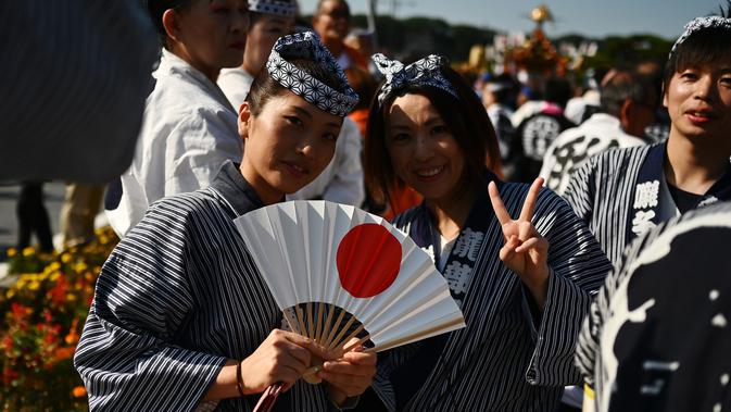 Perayaan Penobatan Kaisar Jepang Naruhito: Dua wanita berpose saat mengikuti perayaan nasional untuk menandai penobatan Kaisar Jepang Naruhito di depan Istana Kekaisaran,Tokyo (9/11/2019). Kaisar Naruhito menjalankan ritual penobatannya setelah dilantik pada 1 Mei 2019. (AFP Photo/Charly Triballeau)