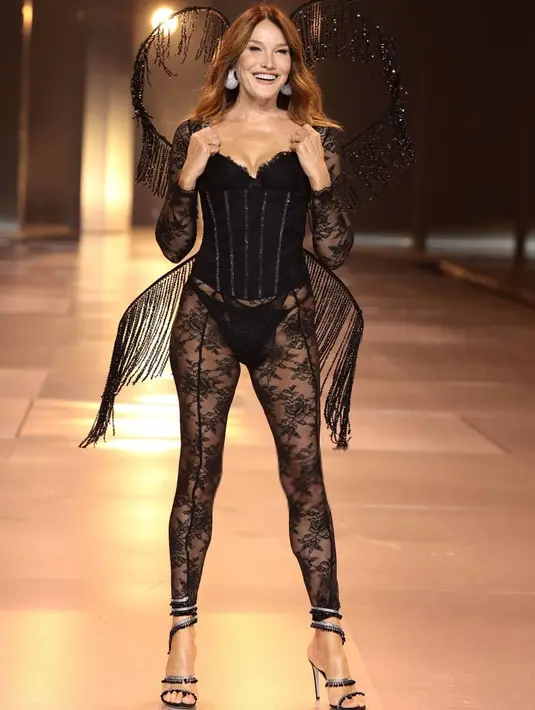 Carla Bruni tampil stunning dengan bustier dan lace pants serba hitam. Ia menyempurnakan penampilannya dengan sayap fringe yang unik. [@runway.dolls]