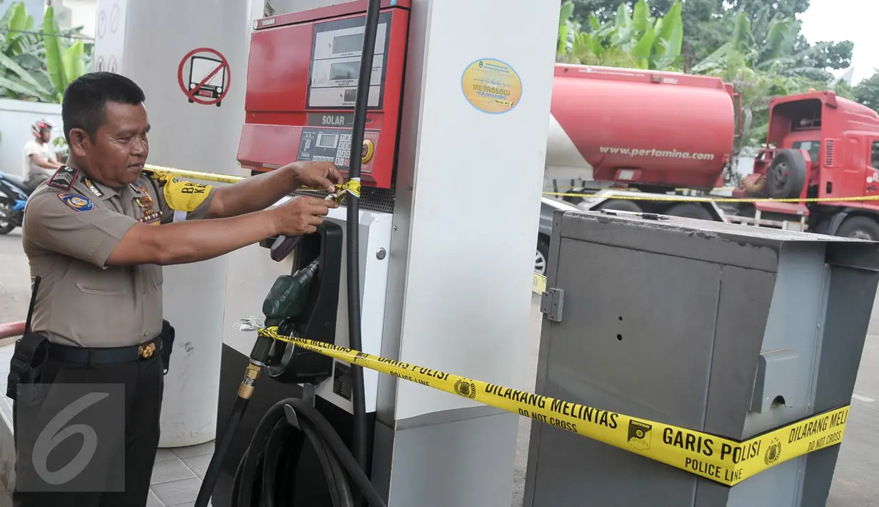 Seorang petugas memeriksa garis polisi yang terpasang di mesin pompa solar di SPBU Jalan Juanda, Depok, Senin (14/11). Polresta Kota Depok menyegel dan menutup sementara SPBU tersebut lantaran diduga mencampur solar dengan air. (Liputan6.com/Yoppy Renato)