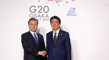 Presiden Korea Selatan (kiri) berjabat tangan dengan Perdana Menteri Jepang Shinzo Abe (kanan) di KTT G-20 tahun 2019 (AFP/Ludovic Marin)