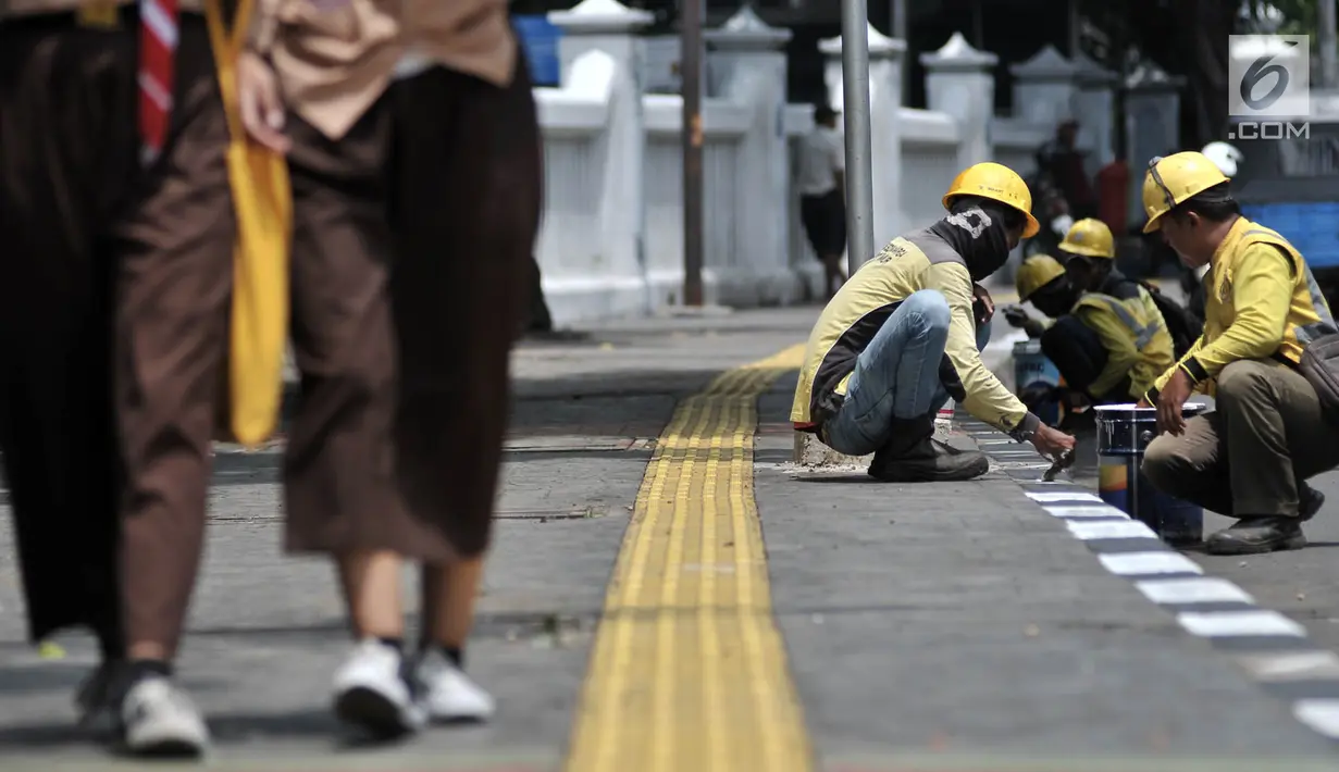 Petugas Suku Dinas Bina Marga Jakarta Timur saat menyelesaikan pengecatan trotoar di Jalan Persahabatan Raya, Jakarta, Rabu (27/3). Kegiatan pengecatan ini rutin dilakukan guna merawat sekaligus mempercantik jalur pedestrian tersebut. (merdeka.com/Iqbal S. Nugroho)