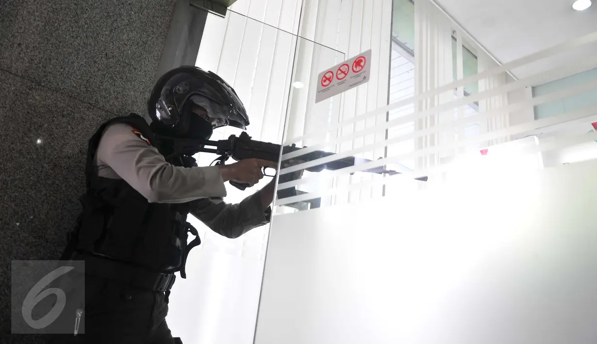 Seorang petugas bersenjata laras panjang tampak membidik ke dalam Gedung Djakarta Theatre, Jakarta, Kamis (14/1). Gedung itu diduga adalah tempat bersembunyi pelaku ledakan Pos Polisi perempatan Sarinah. (Liputan6.com/Gempur M Surya)