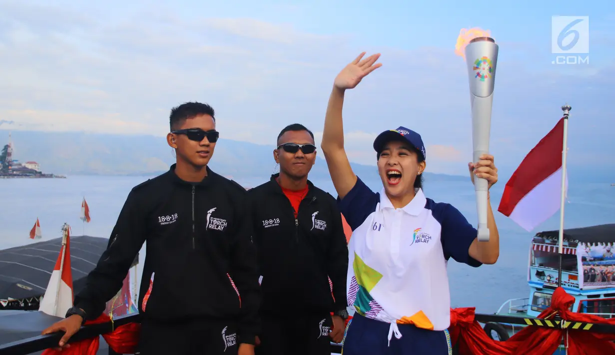 Artis Olivia Zalianty membawa obor Asian Games 2018 berkeliling Danau Toba di Sumatra Utara, Rabu (1/8). Obor Asian Games itu akan di bawa berlayar dengan kapal hias di Danau Toba dan bersepeda menuju pantai bebas Danau Toba. (Liputan6.com/Reza Perdana)