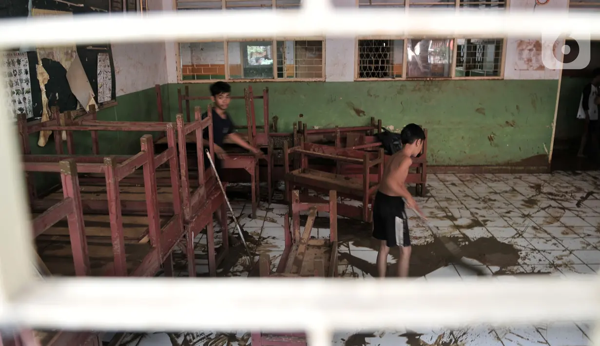 Siswa membantu membersihkan lumpur sisa banjir di SD-SMP Perguruan Rakyat 2, Kampung Melayu Kecil, Kelurahan Bukit Duri, Kecamatan Tebet, Jakarta Selatan, Senin (6/1/2020). (merdeka.com/Iqbal S. Nugroho)