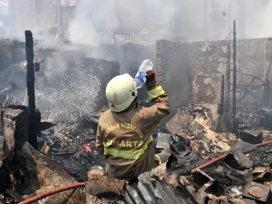 Petugas pemadam kebakaran meminum air saat berusaha menjinakkan api yang melahap permukiman warga di Jalan Kebon Jeruk 13, Taman Sari, Jakarta Barat, Minggu (6/10/2019). Kebakaran menghanguskan puluhan rumah di dua kelurahan, Taman Sari dan Mapar. (merdeka.com/Iqbal Nugroho)