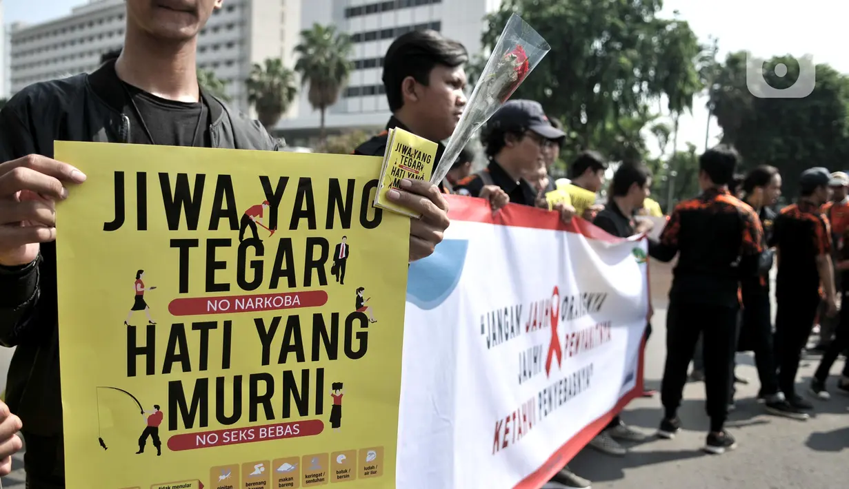 Aktivis membawa spanduk dan poster saat peringatan Hari AIDS Sedunia di kawasan Bundaran HI, Jakarta, Minggu (1/12/2019). Aksi yang digelar Pemuda Pancasila dan Depkes diisi dengan bagi bunga mawar beserta buku panduan tentang penyakit AIDS kepada warga. (merdeka.com/Iqbal S. Nugroho)