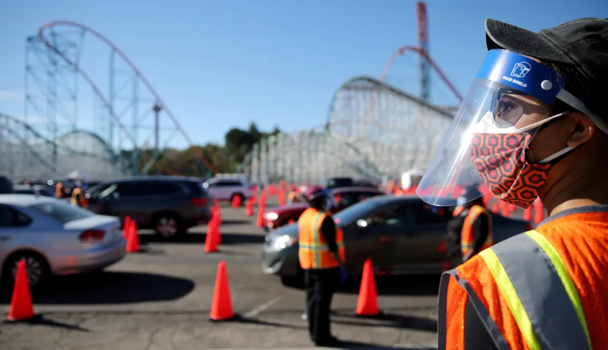 Relawan memandu pengendara di pusat vaksinasi COVID-19 drive-thru massal di tempat parkir Six Flags Magic Mountain di Valencia, California, Selasa (2/2/2021). Situs ini di salah satu dari lima situs vaksin corona utama yang dioperasikan oleh Los Angeles County. (VALERIE MACON/AFP)