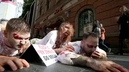 Aktivis PETA berdandan menyerupai zombie sambil berbaring di jalan depan sebuah restoran cepat saji di Sydney, Australia, Kamis (15/6). Aksi tersebut sebagai bentuk protes terhadap konsumsi daging dan mempromosikan vegetarian. (AP Photo/Rick Rycroft) 
