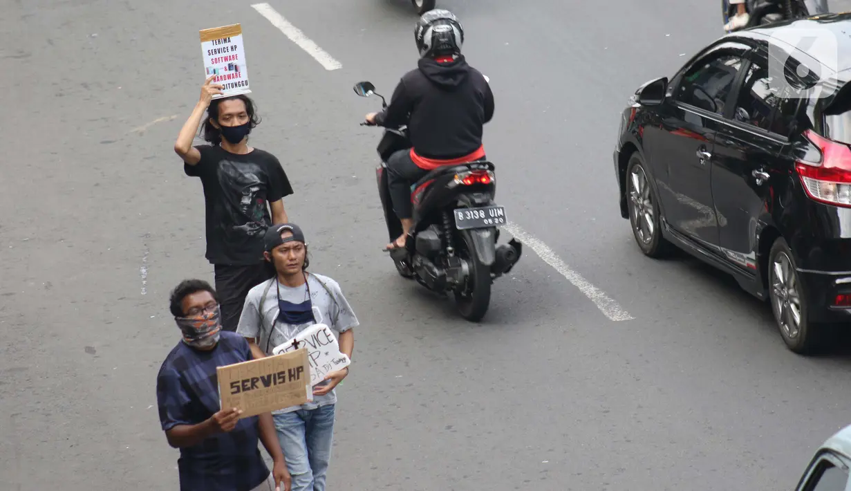 Penjual jasa perbaikan telepon genggam menawarkan jasanya di depan Mall Pusat Grosir Cililitan, Jakarta, Kamis (14/5/2020). Sejak pemberlakuan Pembatasan Sosial Berskala Besar yang berimbas pada penutupan pusat-pusat perbelanjaan, pendapatan mereka turun drastis. (Liputan6.com/Helmi Fithriansyah)