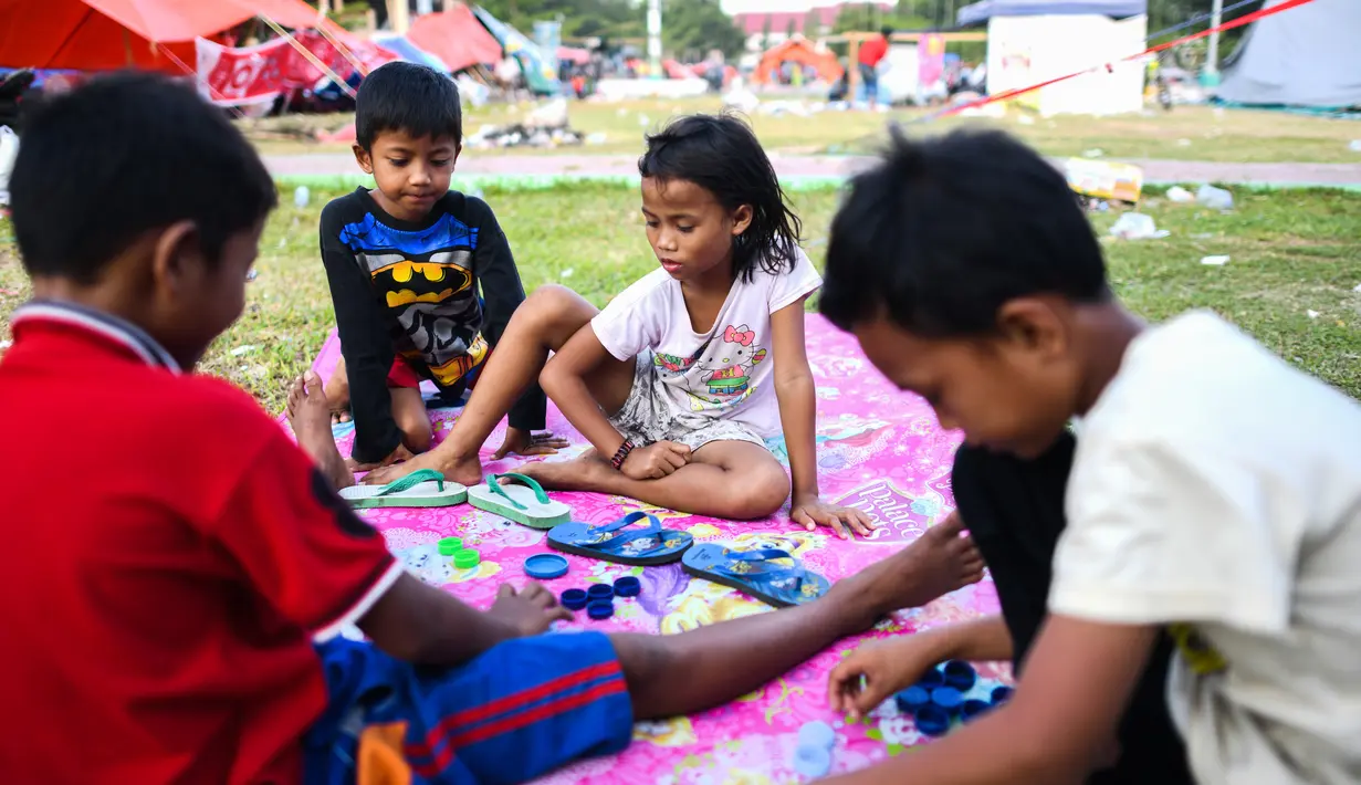 Anak-anak bermain di luar tenda sebuah kamp sementara setelah gempa dan tsunami di Palu, Sulawesi Tengah, Selasa (2/10). Data terbaru BNPB menunjukkan, korban tewas akibat tsunami dan gempa di Sulawesi Tengah sudah mencapai 1.347 orang. (AFP/JEWEL SAMAD)