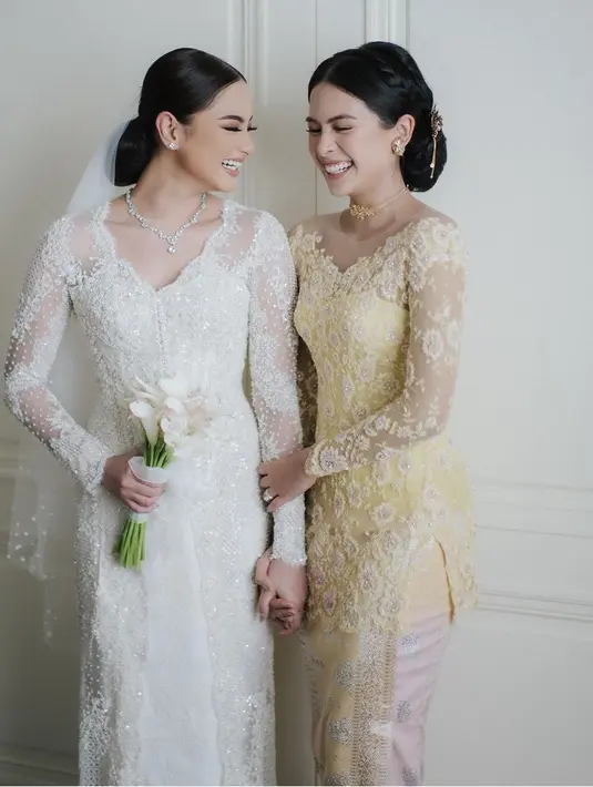 Di pernikahan sang adik, Maudy tampil dengan kebaya kuning brokat model kerah sabrina, yang dipadukan kain songketnya.  [@maudyayunda]