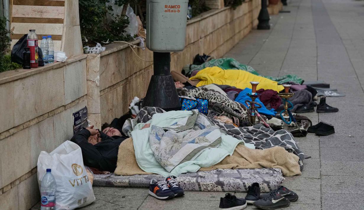 Selain di ruang terbuka, banyak warga yang juga terpaksa menghabiskan malam di dalam mobil yang diparkir di sepanjang jalanan kota. Tampak dalam foto, para pengungsi yang melarikan diri dari serangan udara Israel di Dahiyeh, tidur di tepi Laut Mediterania di Beirut, Lebanon, Sabtu, 7 Maret 2026. (AP Photo/Bilal Hussein)