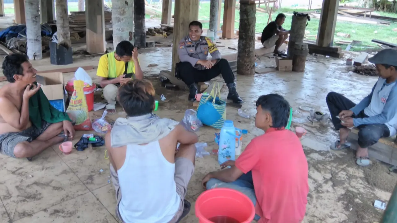 Bhabinkamtibmas Polres Rokan Hulu duduk bersama dengan buruh bangunan bahas hari pencoblosan Pilkada.