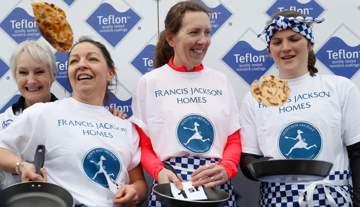 Katie Godof (tengah) berpose setelah memenangkan lomba lari sembari membawa wajan berisi pancake di Olney, Buckinghamshire, Inggris, Selasa (25/2/2020). Para peserta kompetisi tahunan tersebut harus membolak-balikan pancake sambil tetap berlari. (AP/Alastair Grant)