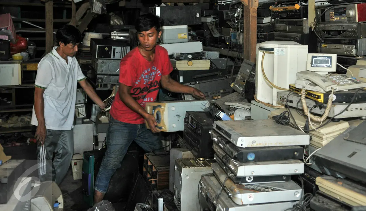 Nurcholis Agi (kiri) bersama pekerjanya saat merapihkan tumpukan barang-barang elektronik bekas disudut ruangan toko Mal Rongsok, Depok, Rabu (17/2). (Liputan6.com/Yoppy Renato)