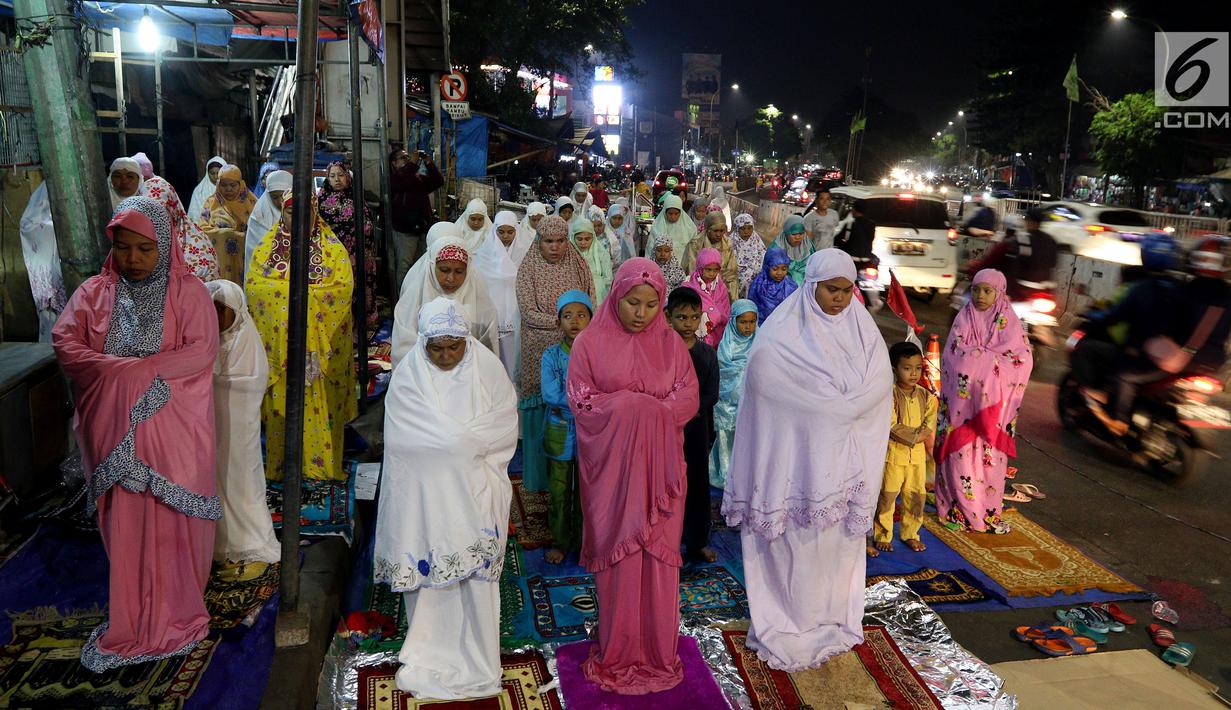 Jemaah wanita melaksanakan salat tarawih hingga ke badan jalan akibat melubernya Musala Miftahul Jannah di Kawasan Pasar Gembrong, Jakarta, Kamis (17/5). (Liputan6.com/JohanTallo)