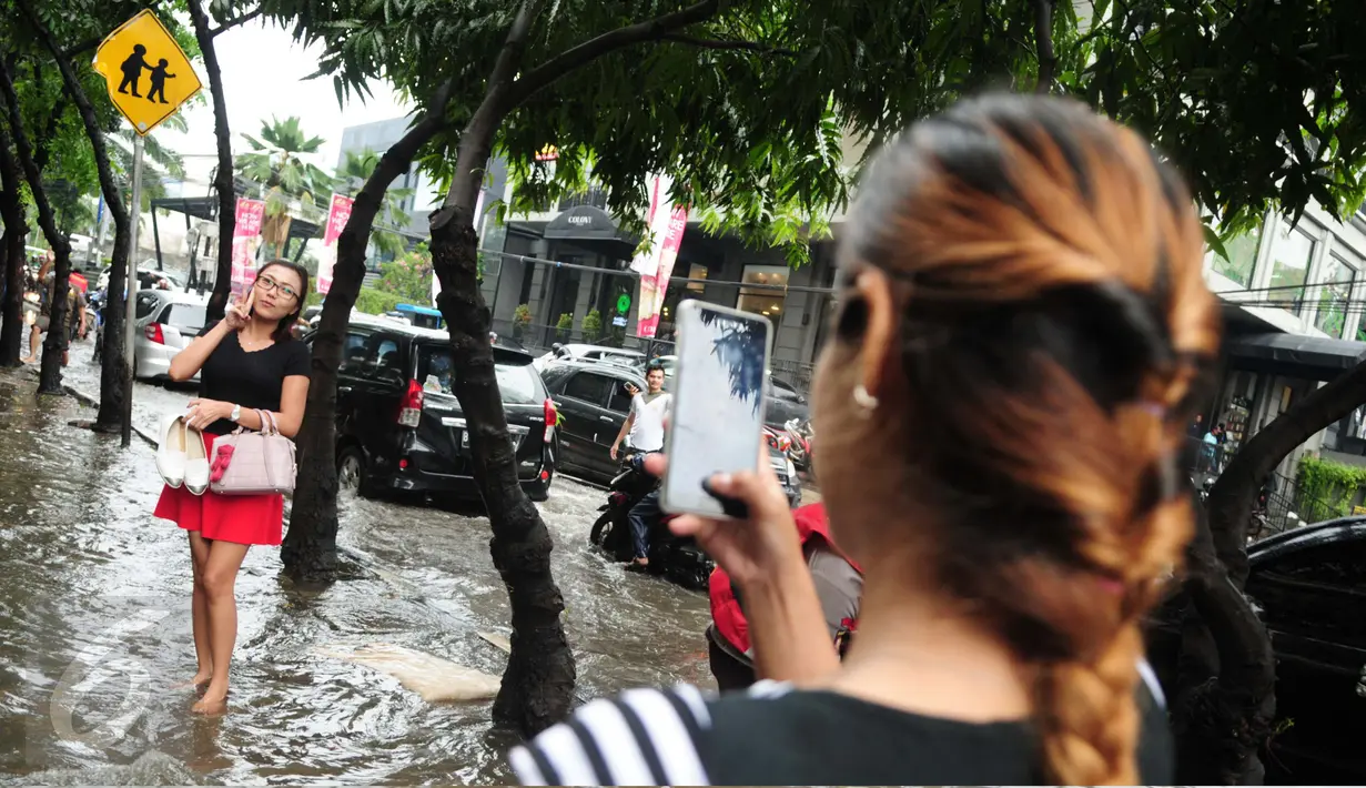 Seorang warga berfoto di tengah banjir yang melanda kawasan Kemang, Jakarta, Selasa (4/10). Hujan deras yang mengguyur Jakarta kembali menyebabkan kawasan Kemang tergenang air hingga setinggi 40 cm (Liputan6.com/Gempur M Surya)