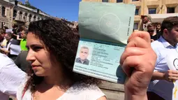 Istri Afgan Mukhtarli menunjukkan passport suaminya saat unjuk rasa di Tbilisi, Georgia, Rabu (31/5). Afgan Mukhtarli adalah wartawan Azerbaijan yang tinggal di Georgia, ia diculik dan disembunyikan di Azerbaijan.(AP Photo / Shakh Aivazov)