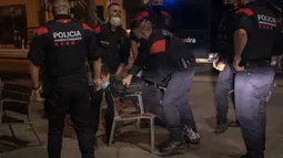 Seorang pemuda ditahan oleh Mossos d'Escuadra, kepolisian regional Catalonia, setelah jam malam di Barcelona pada 1 November 2020. Pemerintah Spanyol menetapkan pembatasan gerak atau jam malam yang berlaku pukul 22.00 untuk mengendalikan lonjakan kasus Covid-19. (AP Photo/Emilio Morenatti)