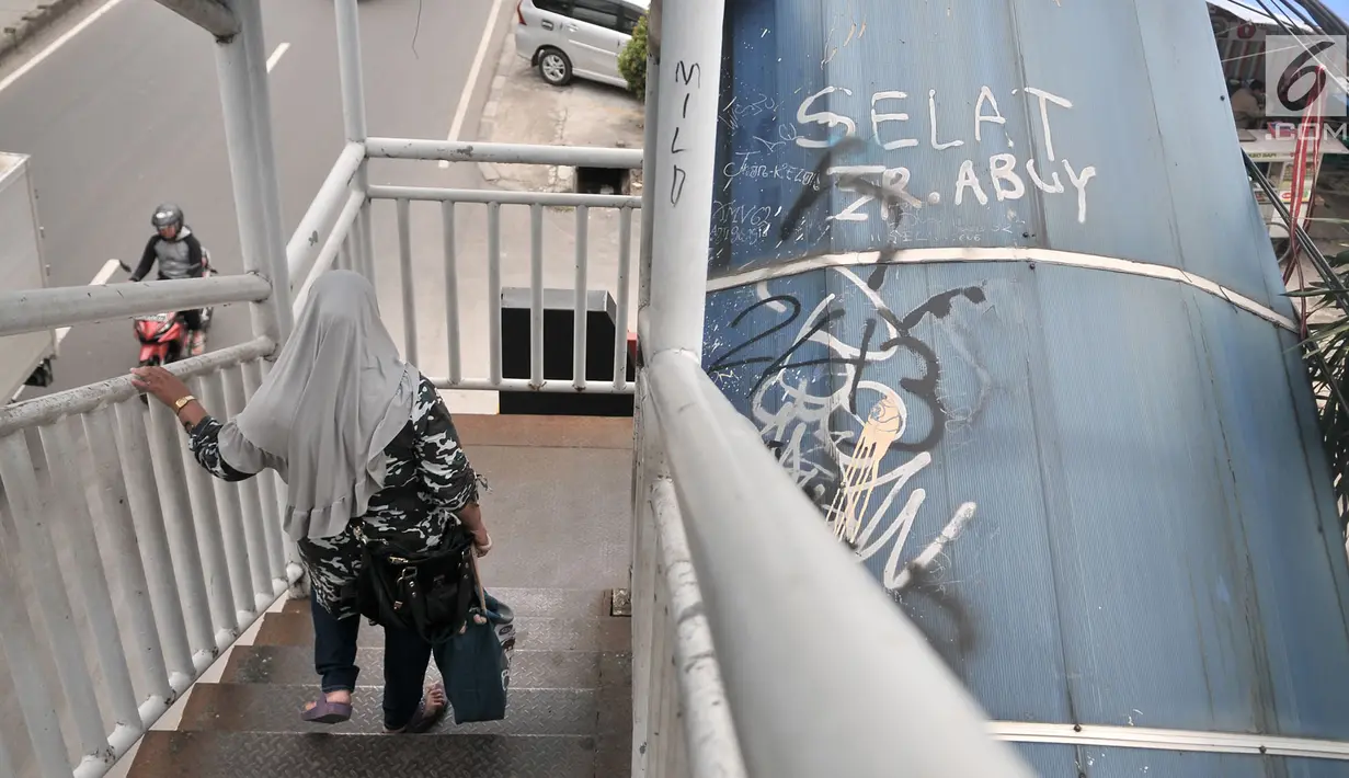 Pejalan kaki melintasi JPO yang tidak terawat di JPO Imigrasi Jakarta Timur, Kamis (17/1). JPO yang berada di depan Kantor Imigrasi Jakarta Timur dalam kondisi tidak terawat, seperti atap yang sudah rusak dan penuh coretan. (Merdeka.com/Iqbal S. Nugroho)