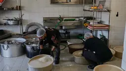 Sejumlah keluarga mengungsi di Institut Teknik Bir Hassan yang telah diubah menjadi tempat penampungan. Tampak dalam foto, para sukarelawan memasak makanan untuk para pengungsi yang menghindari serangan udara Israel di Lebanon selatan dan Dahiyeh, di Institut Teknik Bir Hassan yang telah diubah menjadi tempat penampungan, Beirut, Rabu 11 Maret 2026. (AP Photo/Bilal Hussein)