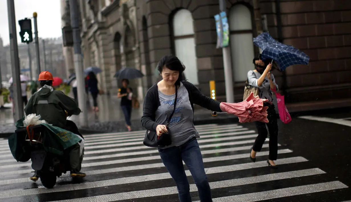 Seorang wanita mencoba melintasi jalanan saat Topan Fung-Wong melintasi daerah dekat pesisir Shanghai, Tiongkok, (23/9/2014). (REUTERS/Carlos Barria)
